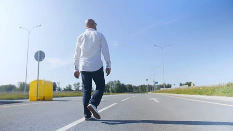 Rear view of a bald man walking along еmpty the road. Full shot. Stock Footage 114133726