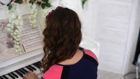 Rear view of beautiful girl playing on a white piano. Man hugs her shoulders Stock Footage