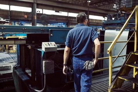 Rear view of blue collar worker working in steel industry Fotos de archivo