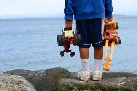 Rear view of boy (8-9) with toys against sea Stock Photos