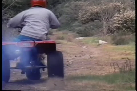 Rear view of boy riding ATC on dirt road Vídeos de archivo 11354039