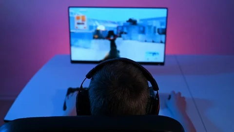 Rear view of boy sitting in front of pc playing FPS video game on computer Stock Footage 100725436