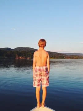 Rear view of a boy standing on bow of a boat ready to jump into the sea, Hof, Stock Photos