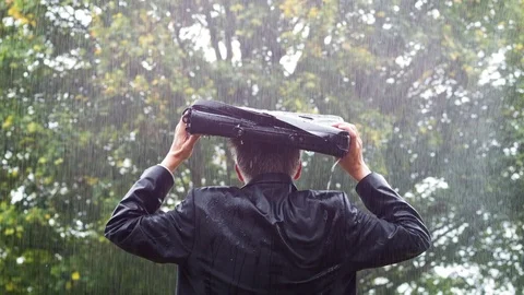 Rear view of a businessman sheltering underneath his bag in the rain Video stock 80927190