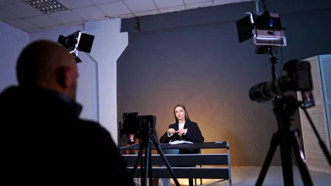 Rear view of a cameraman sitting in front of camera on tripod.  Stock Footage 333579151