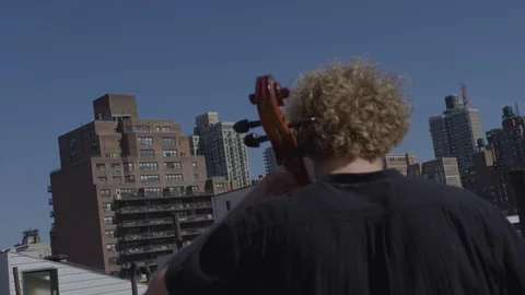 Rear view cellist playing on New York rooftop Stock Footage 111043355