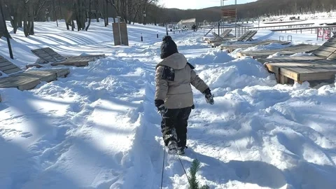 Rear view of a child in snowsuit pulling wooden sleds on a winter day. Stock Footage 232992887