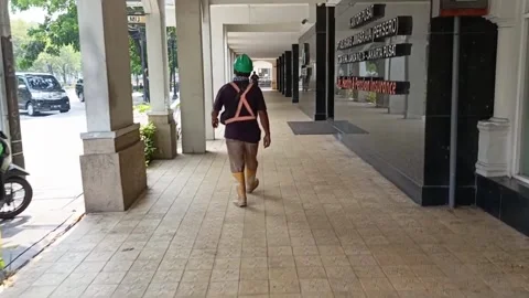 Rear view of a construction worker wearing a safety vest walking on Stock Footage 289921980