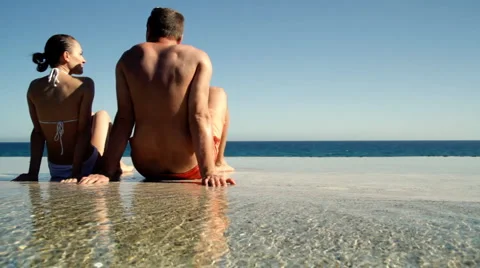 Rear view of a couple sitting on the beach Stock Footage 1068223
