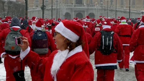 Rear view of crowd of Santa Clauses running in street under heavy snow new year Stock Footage 70646685
