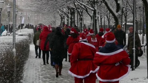 Rear view of crowd of Santa Clauses running in street new year heavy snow Stock Footage 70646752