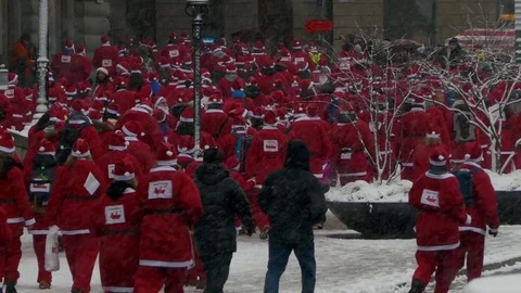 Rear view of crowd of Santa Clauses running in street under heavy snow Stock Footage 70646812