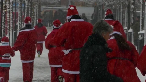 Rear view of crowd of Santa Clauses running in street under new year heavy snow Stock Footage 70646965
