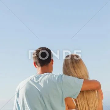 Rear view of cute couple admiring blue sky Stock-Fotos