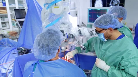 Rear view of the doctor looking at microscope carrying out operation. Stock Footage 309406556