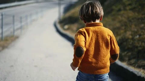 Rear view of an eager young boy, dashing outdoors amidst the fall ambiance... Stock Photos