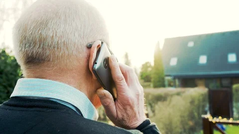 Rear view of elderly man holding smart phone to his ear during conversation Stock Footage 104606957