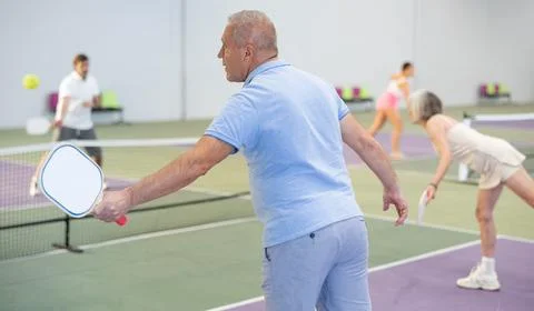 Rear view of elderly man playing pickleball on indoor court Stock Photos