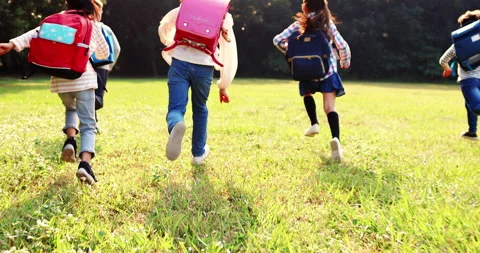 Rear view of elementary school kids running on the grass Stock Footage 143256706