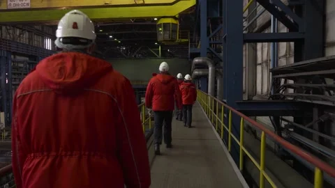 Rear view of engineers in red uniforms walking through a heavy industry factory 스톡 동영상 177541610