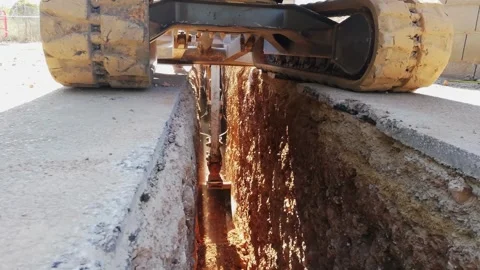 Rear view of the excavator chains digging a trench on a construction site Stock Footage 279227551
