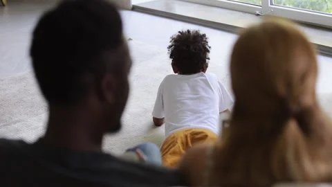 Rear view of family sit on couch and browsing tablet. Spbi afro dad and Stock Footage 135797953