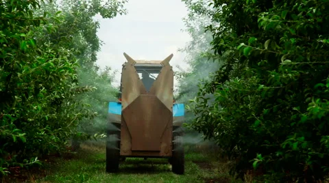 A Rear view of the Fan Sprayer applying Chemicals in an Apple orchard Stock Footage 64905326