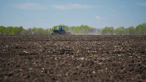 Rear view of a farmer on a tractor sowing grains of corn in a dry agricultural Stock Footage 281931355