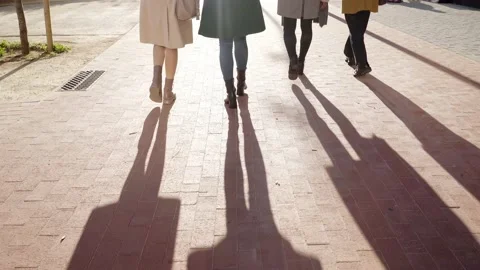 Rear view feet of four unrecognizable faceless people walk outside on a sunny Stock Footage 232328797
