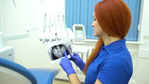Rear view of female dentist looking at dental Xray in clinic Stock Footage 153757944