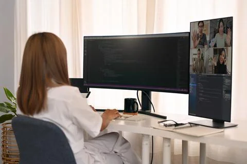 Rear view of female developer having video conference and working with coded Foto stock