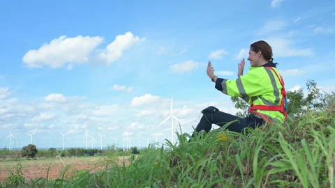 Rear view of female engineer sitting in wind turbine field Stock Footage 253986905