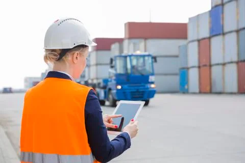 Rear view of female engineer using tablet PC in shipping yard Stock Photos