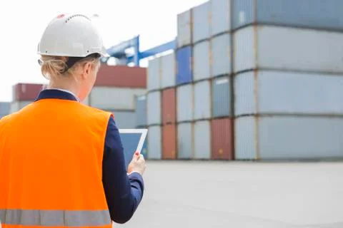 Rear view of female engineer using digital tablet in shipping yard Stock Photos