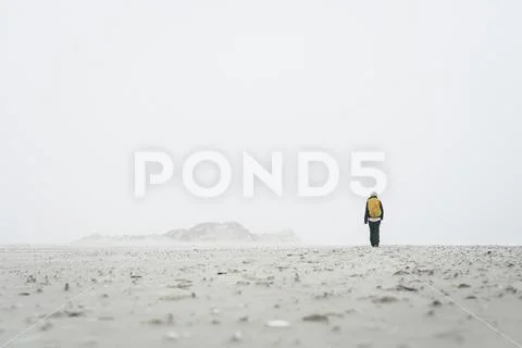 Rear view of female hiker walking on field against sky in foggy weather Stock Photos