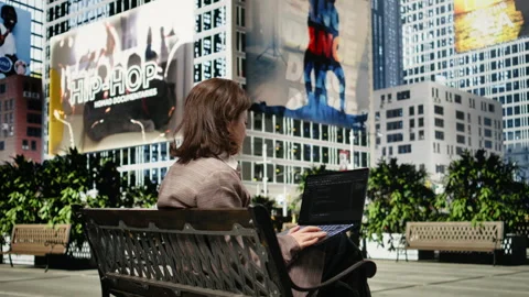 Rear view of female programmer on park bench writing code on laptop Video stock 343554026
