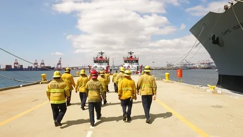 Rear view of fire crews walking toward the fireboats on Port of Long Beach Stock Footage 116493612