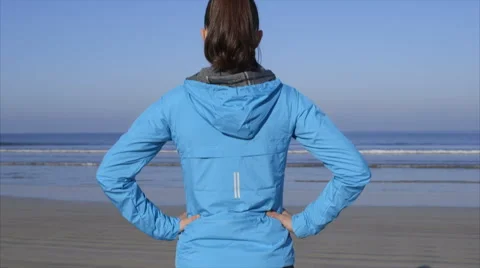 Rear view of fit woman standing on beach watching waves Stock Footage 59081836