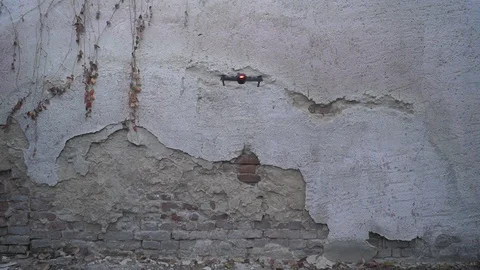 Rear view of foldable drone hovering in front of the old wall Stock Footage 98378716