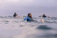 Rear View Of Friends Surfing In Sea Against Sky Stock Photos