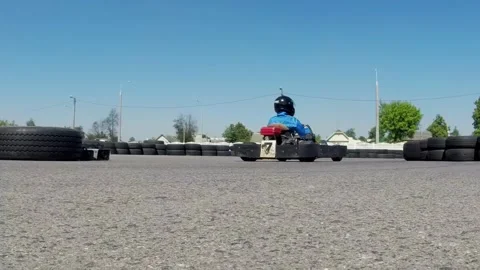 Rear view of a go-kart speeding away on an open track. The racer in blue drives 스톡 동영상 325698033