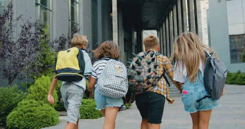 Rear view. Good-looking school child friends climb stairs going to class with Stock Footage 248626139