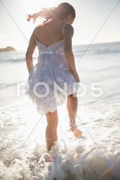 Rear view of gorgeous woman jumping in the waves Stock Photos