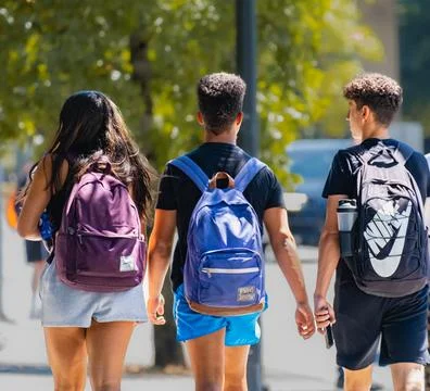 Rear view of a group of university students walking away on a school hallwa.. Stock Photos