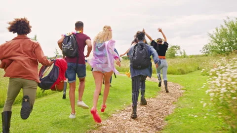 Rear View Of Group Of Young Friends Running Through Entrance Barrier Onto Music Stock Footage 312677289
