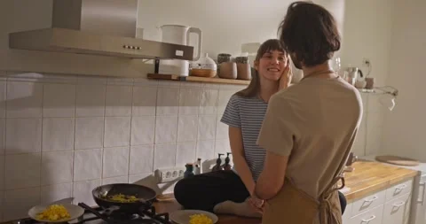 Rear view of guy gently stroking his girlfriend face while making breakfast in Vídeos de archivo 316181100