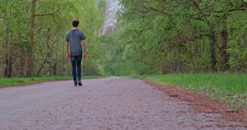Rear view to the Guy  strolling on the nature. Young slim man is walking alon Stock Footage 131044082