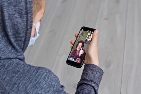 Rear view of a guy talking on a video call with a smiling elderly grandmother Stock Photos