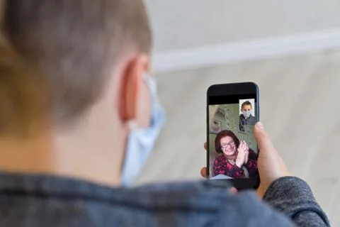 Rear view of a guy talking on a video call with a smiling elderly grandmother Stock Photos