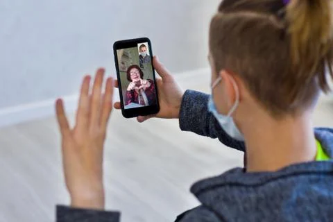 Rear view of a guy talking on a video call with a smiling elderly grandmother Stock Photos